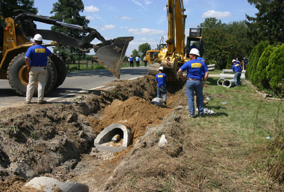 Pamar crew in hard hats setting concrete pipe in an open roadside trench