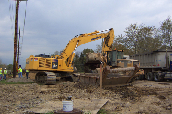 Pamar excavator loading a haul truck beside a residential street